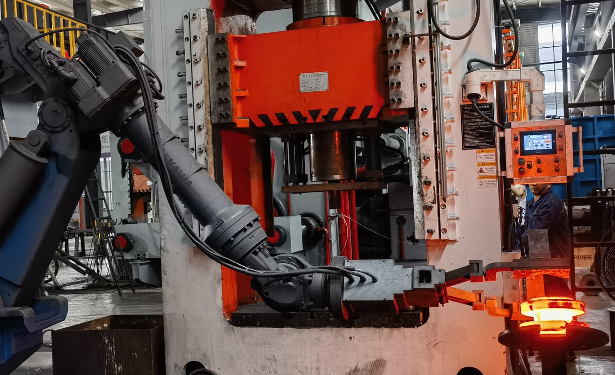 Side view of the manipulator feeding a hot billet into the press die